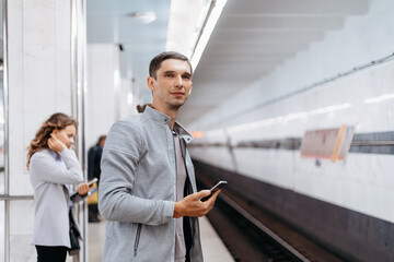 Fototapeta premium young man waiting for a train on the subway platform.