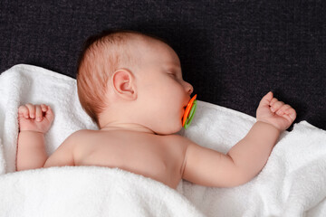 Newborns Concepts. Macro Shoot Of Peacefully Sleeping Cute Newborn Baby With Dummy On White Blanket.