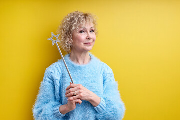 charming lady 60 years old with magic wand in hands looking at camera