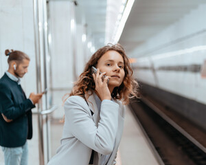 young woman with a smartphone standing on the subway platform.