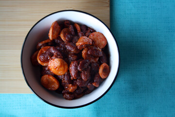 Red beans with sausages stewed in tomato paste in a white bowl.