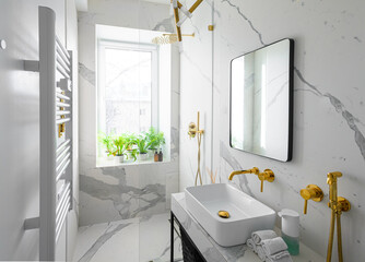 Modern luxury bathroom interior with white marble tiles and golden accessories 
