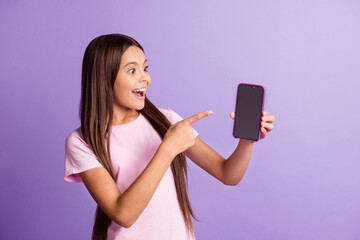 Naklejka premium Photo of pretty excited young girl wear pink t-shirt looking pointing modern gadget empty space isolated violet color background