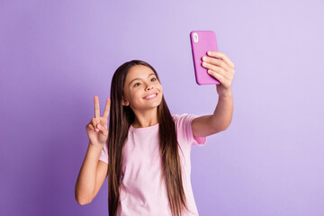 Photo of charming cute schoolgirl dressed t-shirt tacking selfie modern device showing v-sign isolated purple color background