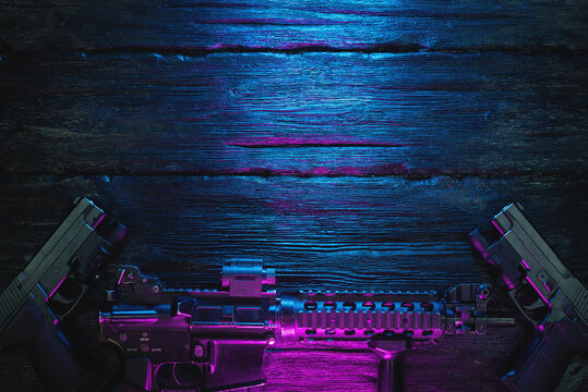 Airsoft rifle and guns on the flat lay table background with copy space. Cyberpunk weapon concept.