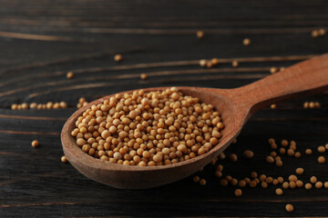 Wood spoon with mustard seeds on wooden background