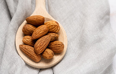 Almonds on wooden spoon on the grey napkin as background.Selective focus.Top view wit copy space.