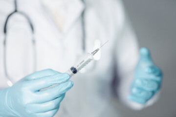 A doctor or scientist in a laboratory develops a medical vaccine. Holds a syringe with liquid vaccines to study and analyze antibody samples for new strain of COVID-19 patients in 2021.
