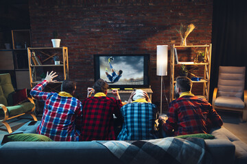Group of friends watching TV, sport match together. Emotional fans cheering for favourite team,...