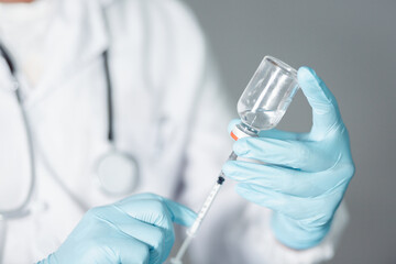 A doctor or scientist in a laboratory develops a medical vaccine. Holds a syringe with liquid vaccines to study and analyze antibody samples for new strain of COVID-19 patients in 2021.
