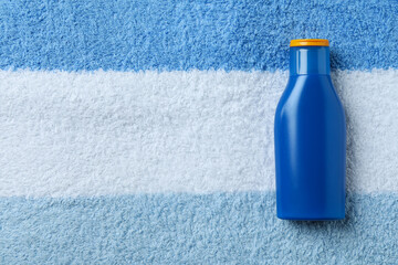 Blue bottle of sunscreen on towel background