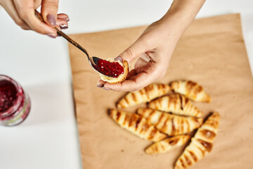 Person spreading jam on freshly baked homemade croissants