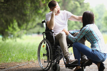 Disabled man in wheelchair communicates with woman in park