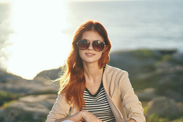 happy traveler at sunset in the mountains near the sea in summer glasses striped t-shirt sweater