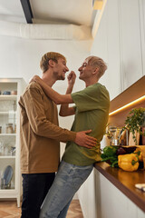 Happy male lovers hugging near table with fresh grocery