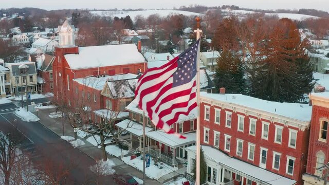 Separation Of Church And State Theme. American Flag Over Historic Small Town In United States Of America. Winter Snow Scene.