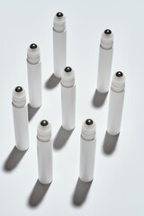 Many tubes for eye roller beauty product isolated over white background with reflection