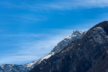 Snowcapped mountain range of the Monte Bondone in winter (2180 m) with the telecommunications antennas, seen from the Trento city, Adige Valley, Trentino Alto Adige, Italy, Europe.