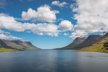 Ocean fjord of Seydisfjordur, Iceland, on a warm, partly cloudy day.