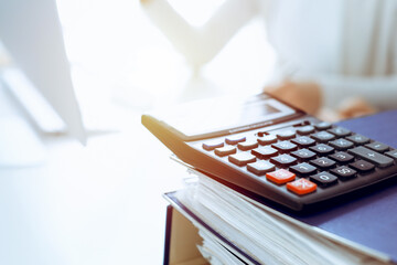 Calculator and binders with papers are waiting to be processed by business woman or bookkeeper...