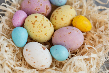Happy Easter holiday concept. nest decorations background with chocolate Easter eggs. Festive food background. Holiday symbol. candy covered eggs in various pastel colors. Selective focus