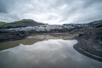 Long exposure of Icelandic glacier by glacier lagoon. Glacier reflects in water.