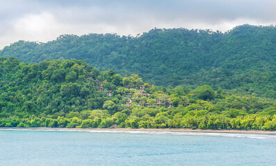 Mountainous, tropical, beautiful green nature with houses in Costa Rica near the ocean. Central America.