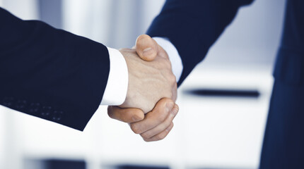 Business people shaking hands after contract signing while standing in a modern office. Teamwork and handshake concept