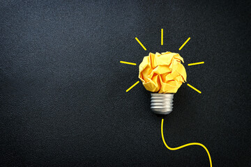 Education concept image. Creative idea and innovation. Crumpled paper as light bulb metaphor over black background