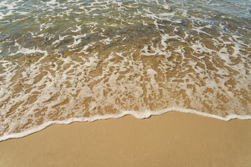 Water with spray on the beach with sand in summer
