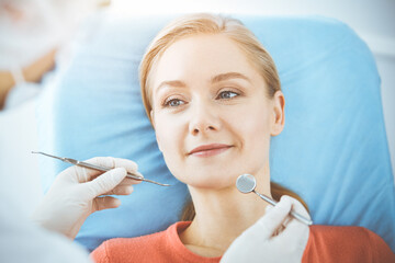 Happy woman is being examined by dentist at dental clinic. Healthy teeth and medicine, stomatology concept