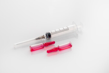 Ampoules with a medicine and a syringe on a light background. Coronavirus vaccine. Medical concept. Isolate.