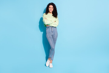 Photo of self-assured lady curly hairstyle crossed hands wear sweater jeans footwear isolated blue...