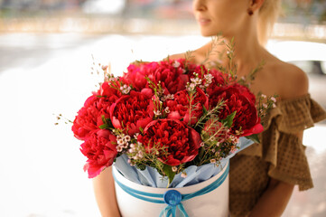 Close-up view of flower arrangement of red peonies in hands of woman