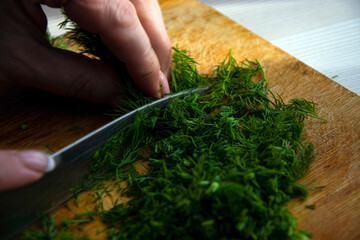 Slicing green dill on a board.