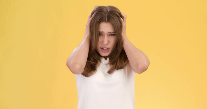 Panic feeling. Young worried woman with mental disorder looking around, grabbing her hair, feeling discomfort