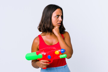 Young mixed race woman holding a water gun isolated suffers pain in throat due a virus or infection.