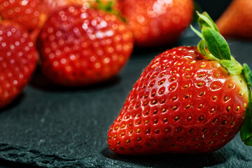 Close up of red strawberries lying on a slate. Selective focus with blur.