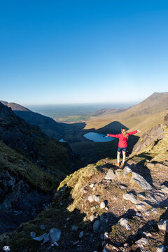 happy woman raising her arms on top of devils ladder with two lakes in background on Carrantuohill mountain