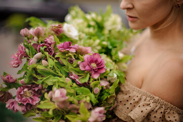 Naklejka premium Close-up view on bunch of colorful bright flowers and green leaves in the hands of woman