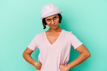 Fototapeta premium Young mixed race woman isolated on blue background frowning face in displeasure, keeps arms folded.