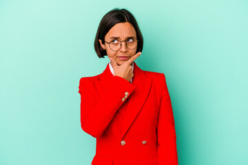 Young mixed race woman isolated on blue background contemplating, planning a strategy, thinking about the way of a business.