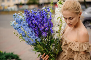young attractive blonde woman with bunch of multicolored delphinium flowers