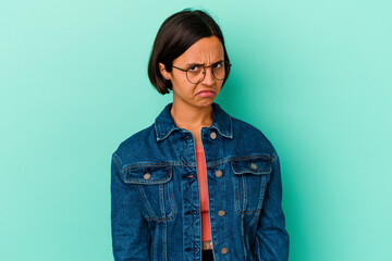 Young mixed race woman isolated on blue background sad, serious face, feeling miserable and displeased.