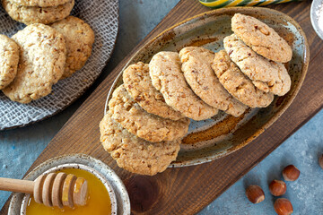 Cookies with almonds-Polvorones on a wooden, textured board with honey and hazelnuts. Top view. Spanish traditional sweetness..