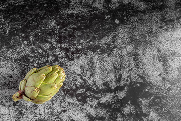 Flat lay moody dark food photography of a fresh artichoke with copy space. Top view image with a...