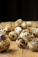 Obraz premium Top view of a group of quail eggs, selective focus, on wooden table and black background, vertical, with copy space