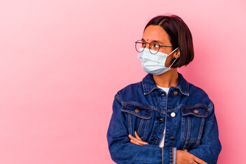 Young Indian woman wearing a mask antivirus isolated on pink background smiling confident with crossed arms.