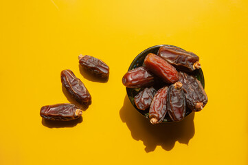 dried dates in bowl and scattered around on yellow ground
