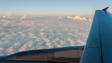 Fototapeta na wymiar Aerial view for Himalayas mountains on the sunset from the airplane porthole. Travel concept